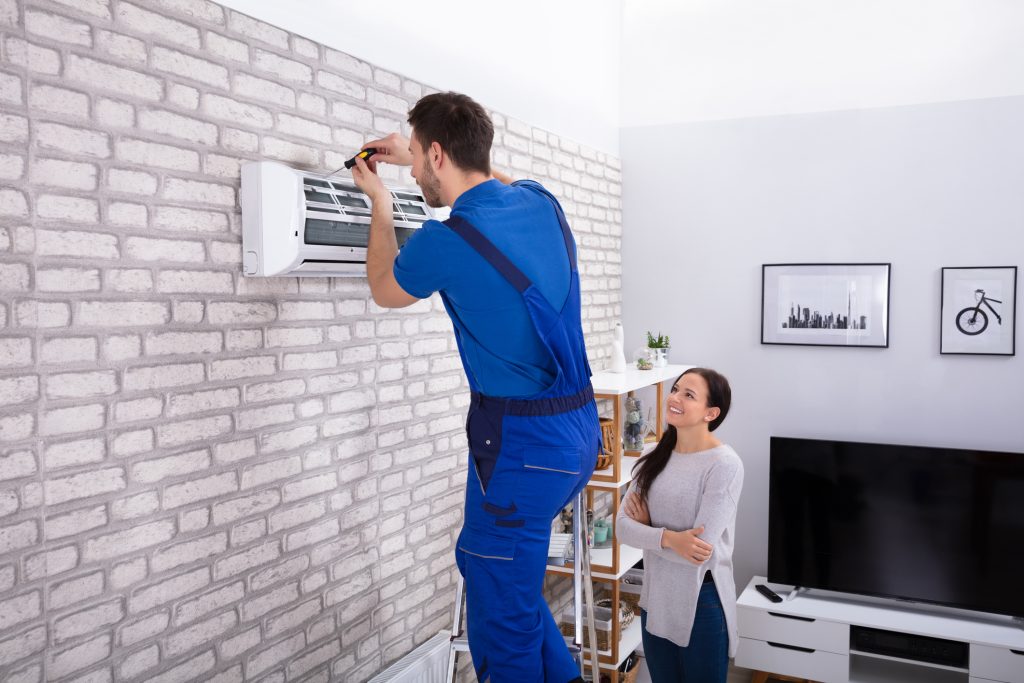Male Technician Repairing Air Conditioner With Screwdriver