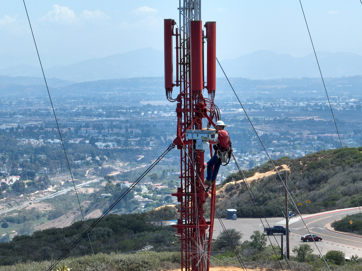 Engineer with safety equipment on high tower for working telecom communication maintenance.