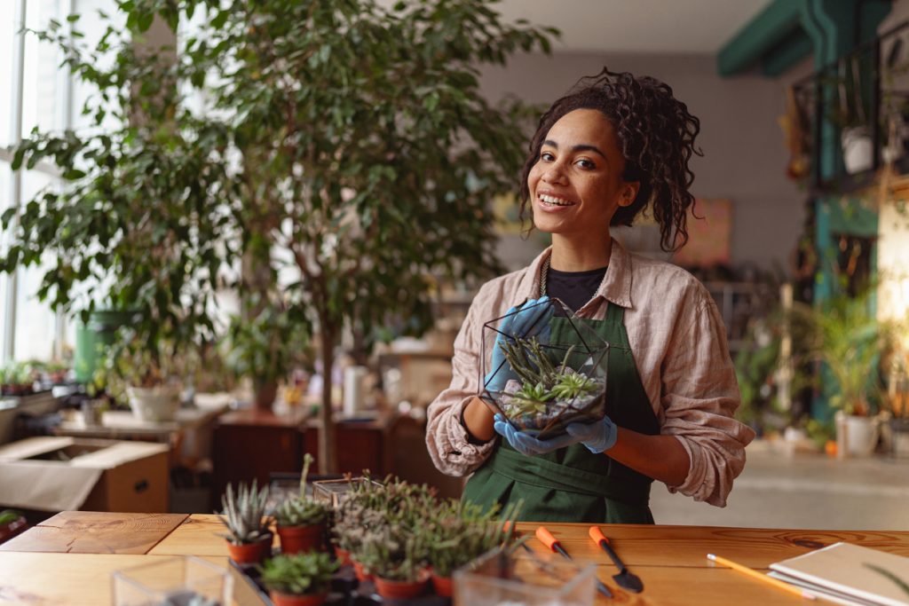 Portrait of smiling woman florist presenting beautiful floral composition with succulent plant