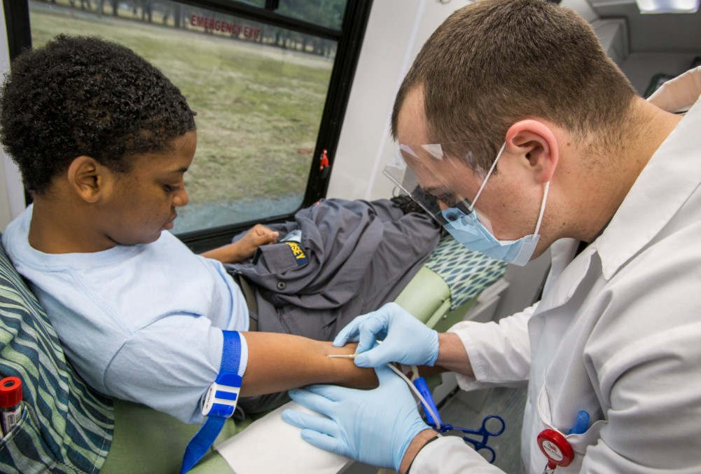 phlebotomist taking blood test from teenager