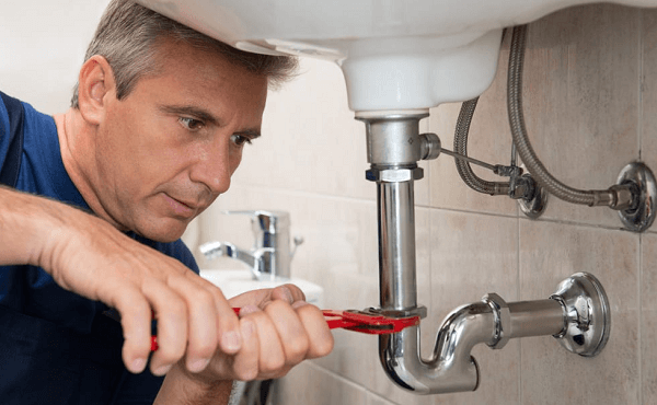 plumber fixing pipes under the sink